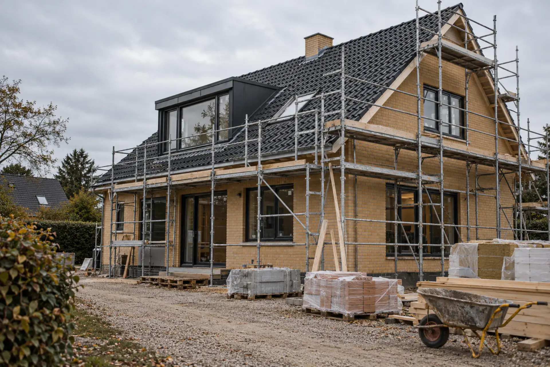 Nybygget hus under opførelse med stillads og byggeudstyr.
